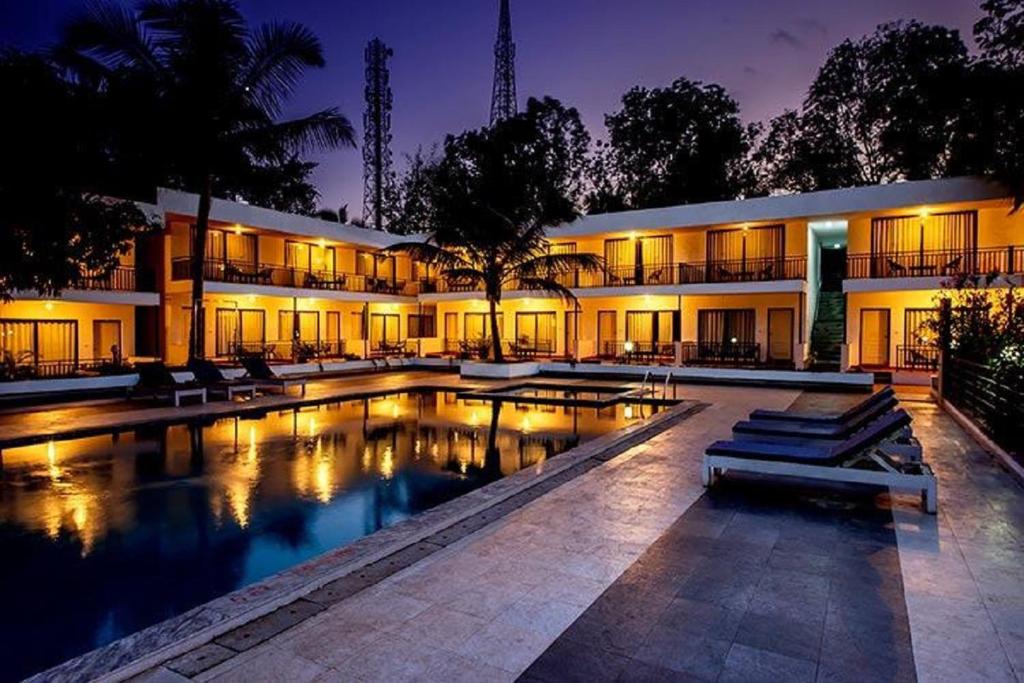 a building with a pool in front of it at night at The Byke Royal Pearl Anjuna in Anjuna