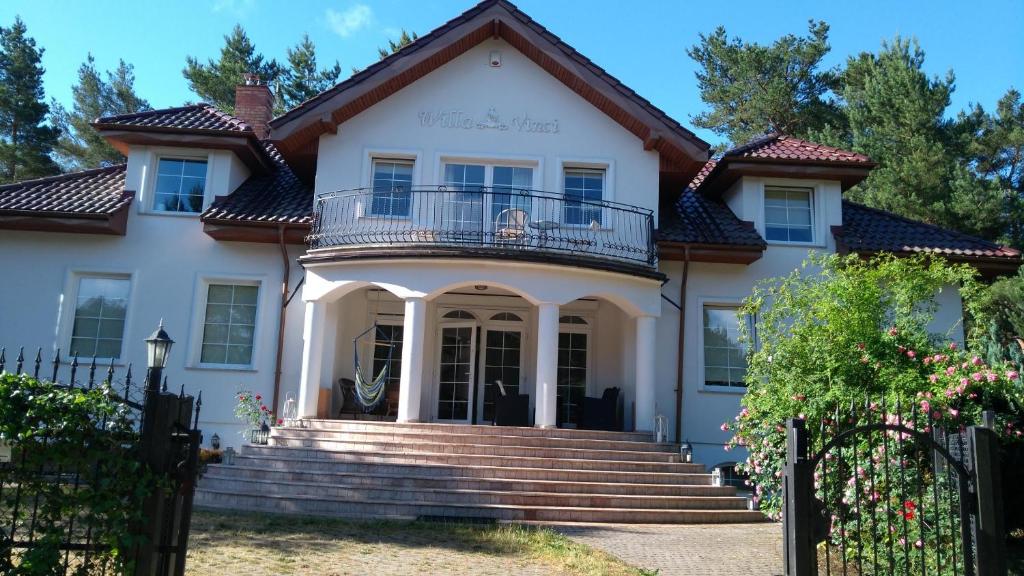 a white house with a balcony and stairs at Willa Vinci Rozewie in Jastrzębia Góra