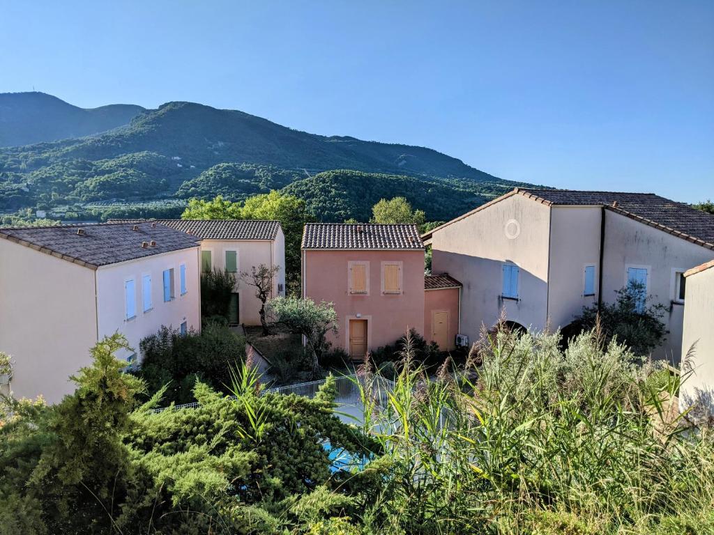 una fila de casas con montañas en el fondo en Maisonnette dans domaine avec piscine à Nyons, pays des olives, en Nyons