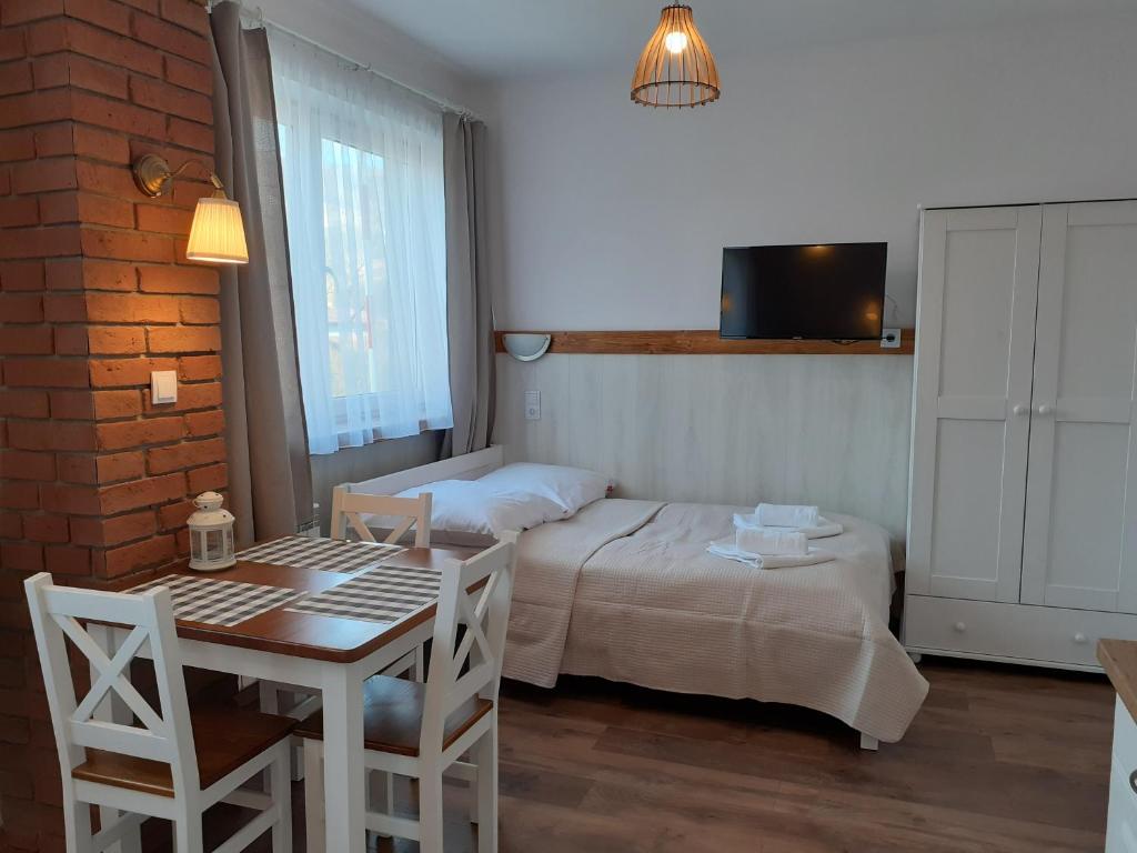 a bedroom with a bed and a table and a table and chairs at Apartamenty nad Jeziorem in Międzybrodzie Żywieckie