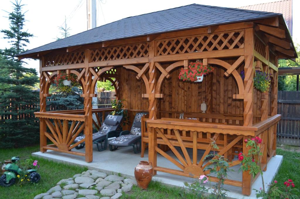 a wooden gazebo with a bench in a yard at Vila Iulia in Bran