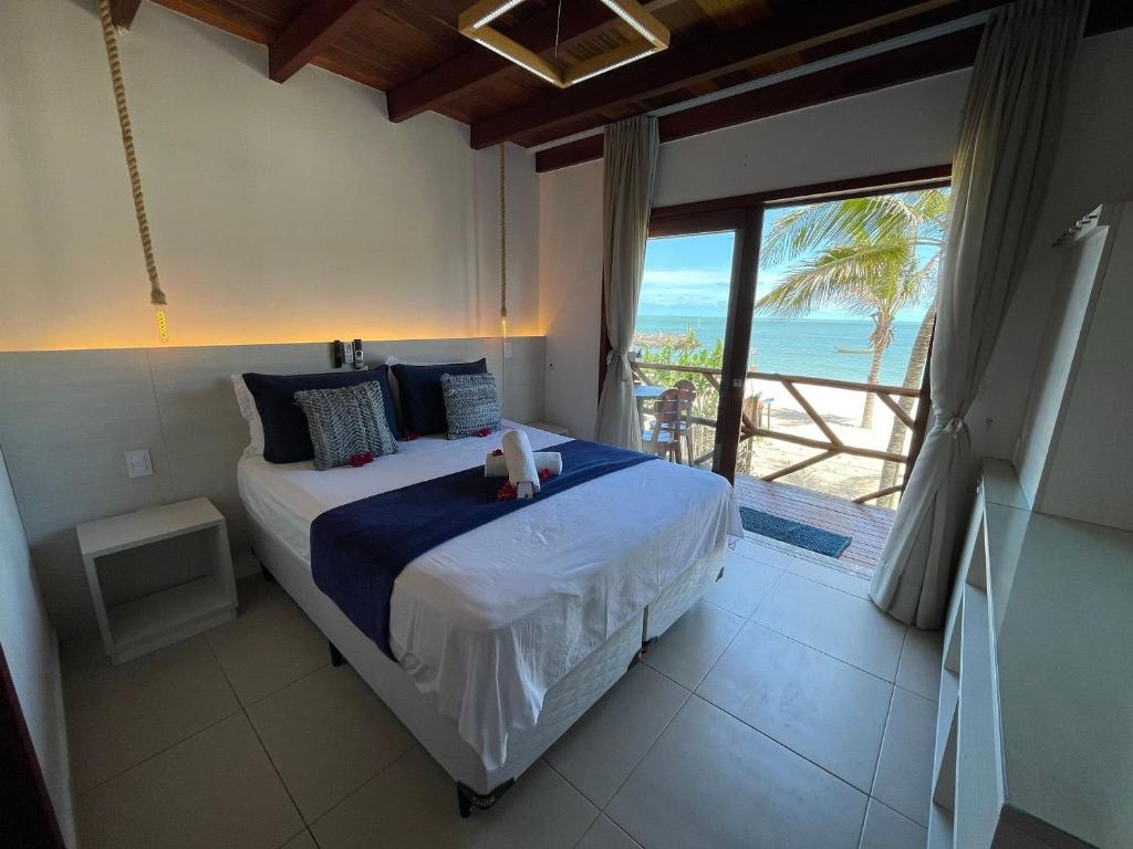 Schlafzimmer mit einem Bett und Meerblick in der Unterkunft Ap. Peixe Boi Pé na areia com vista frontal e total para o mar in Barra Grande