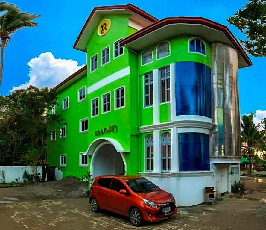 a green building with a red car parked in front of it at Pagudpud Rinnovati in Pagudpud