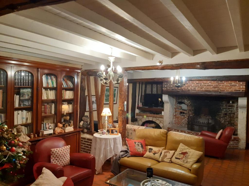 a living room with a couch and a fireplace at les orchidees sauvages in Touffreville-la-Corbeline