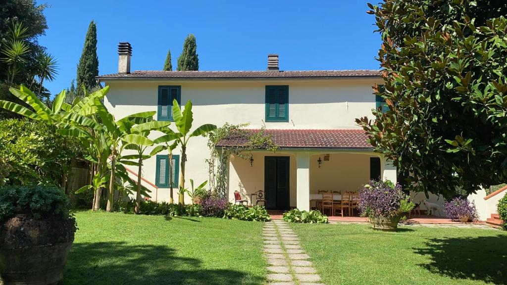 Biały dom z niebieskimi okiennicami i ogródkiem w obiekcie Casa del Pino w mieście Borgo a Buggiano