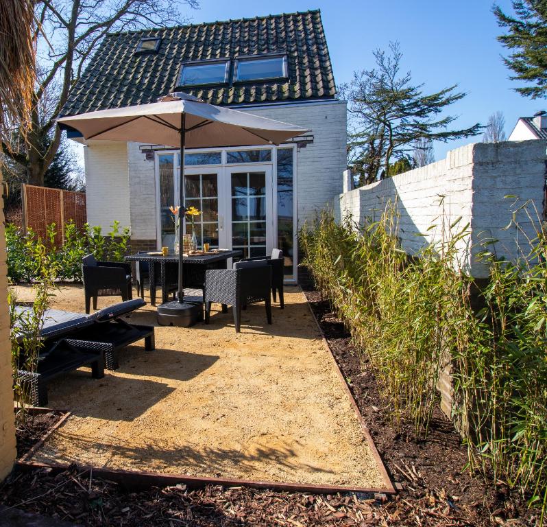 un patio con sombrilla, mesa y sillas en Wellness Lodge aan de Braassem, en Rijnsaterwoude