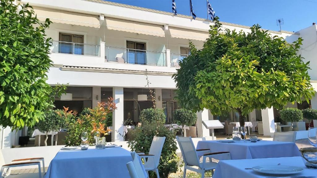a restaurant with blue tables and chairs in front of a building at Akrogiali Exclusive Hotel (Adults Only) in Polykhrono