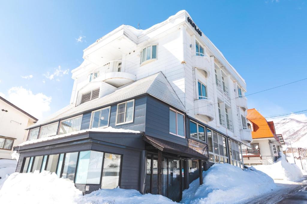 a large white building with snow around it at UNPLAN Village Hakuba in Otari