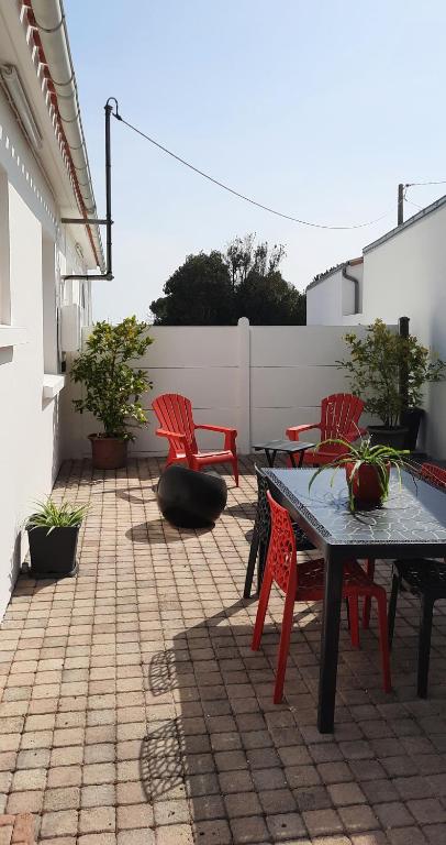 d'une terrasse avec des chaises rouges, une table et des chaises. dans l'établissement Ma maison au bord de la mer, à Saint-Hilaire-de-Riez