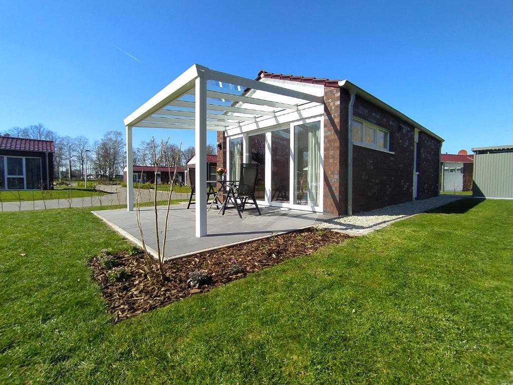 a screened in porch on a house in a yard at Holiday Bungalow am Quendorfer See in Schüttorf