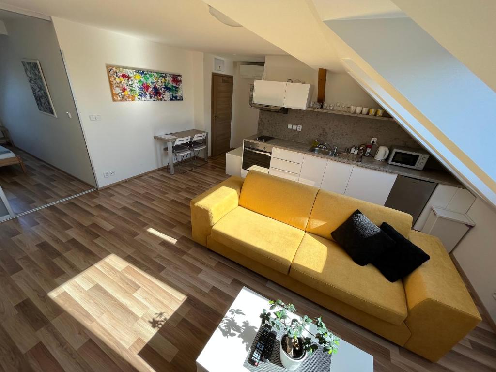 sala de estar con sofá amarillo y cocina en Apartmány Skryjova en Brno