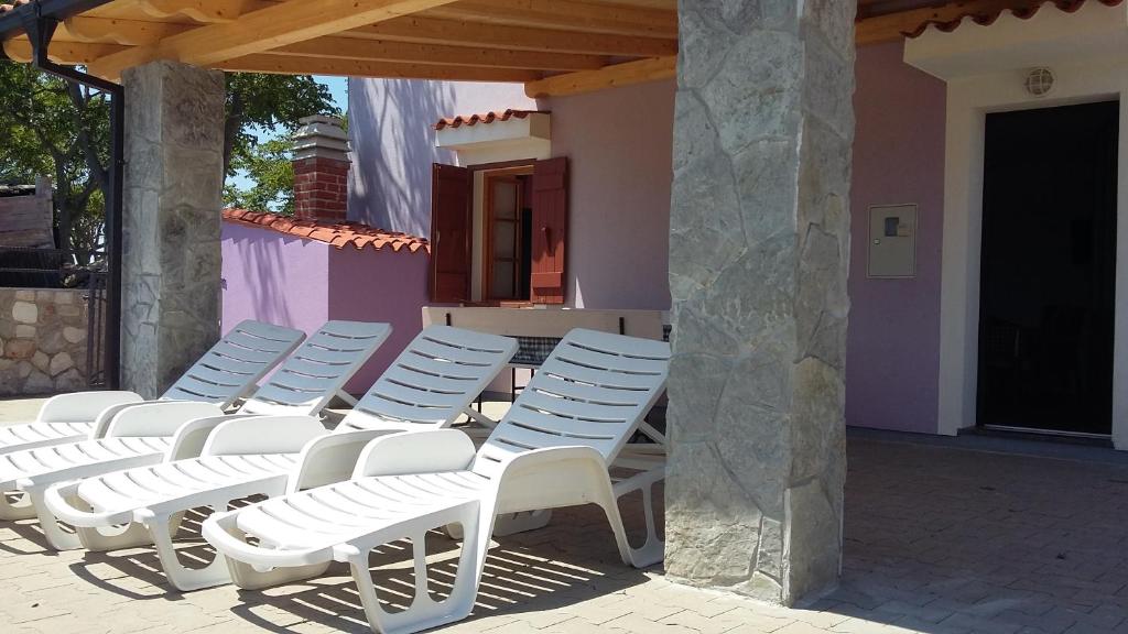 a row of white chairs sitting on a patio at Apartman Kornu in Veli Lošinj