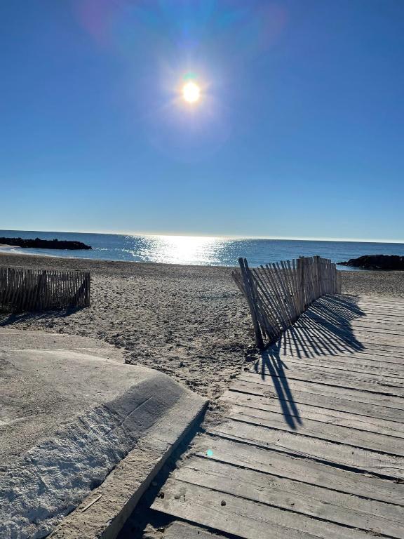 un banc sur une plage avec le soleil dans le ciel dans l'établissement Soleil des Marquises, à Frontignan