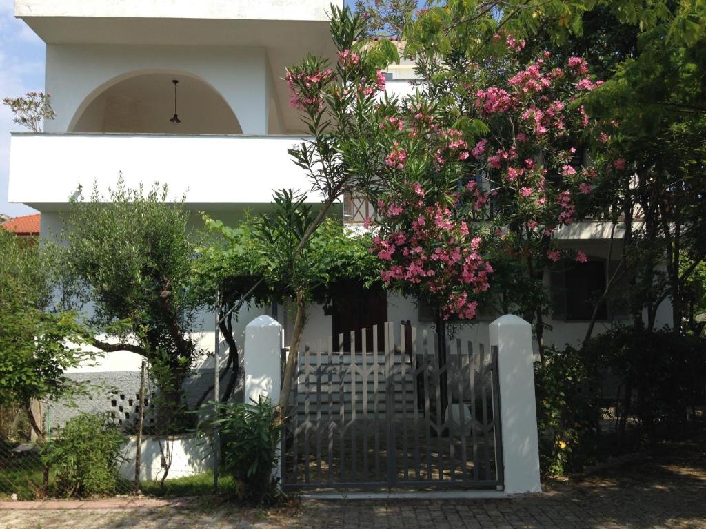 a white house with a gate with pink flowers at Summer Den Plus in Ierissos