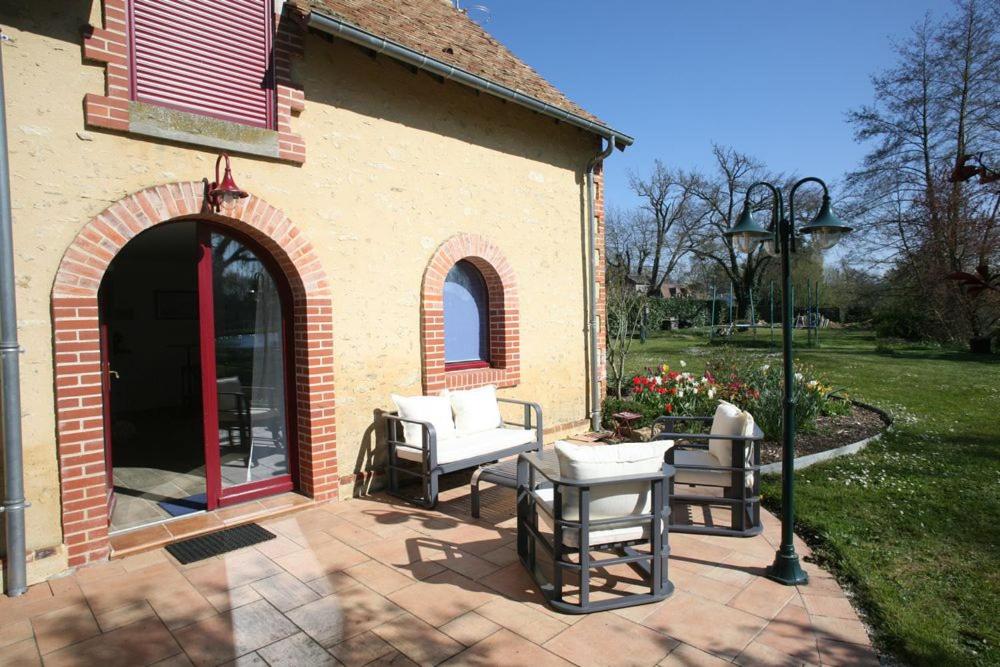 een patio met stoelen en een tafel en een gebouw bij Le Clos Bener in Yvré-lʼÉvêque