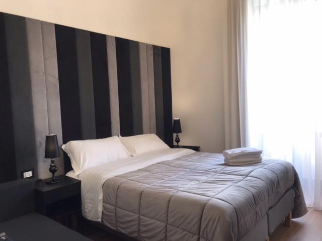 een slaapkamer met een bed met een zwart-wit hoofdeinde bij Motta Palace Apartments & Rooms in Motta SantʼAnastasia