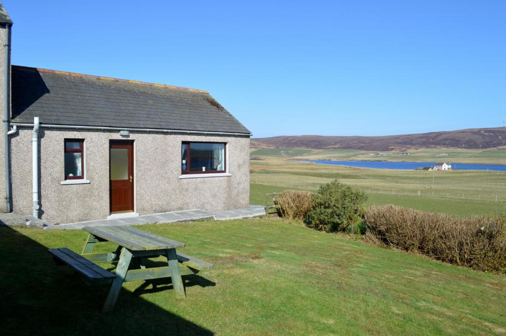 a picnic table in front of a small house at Bachylis Self Catering in Kirkwall