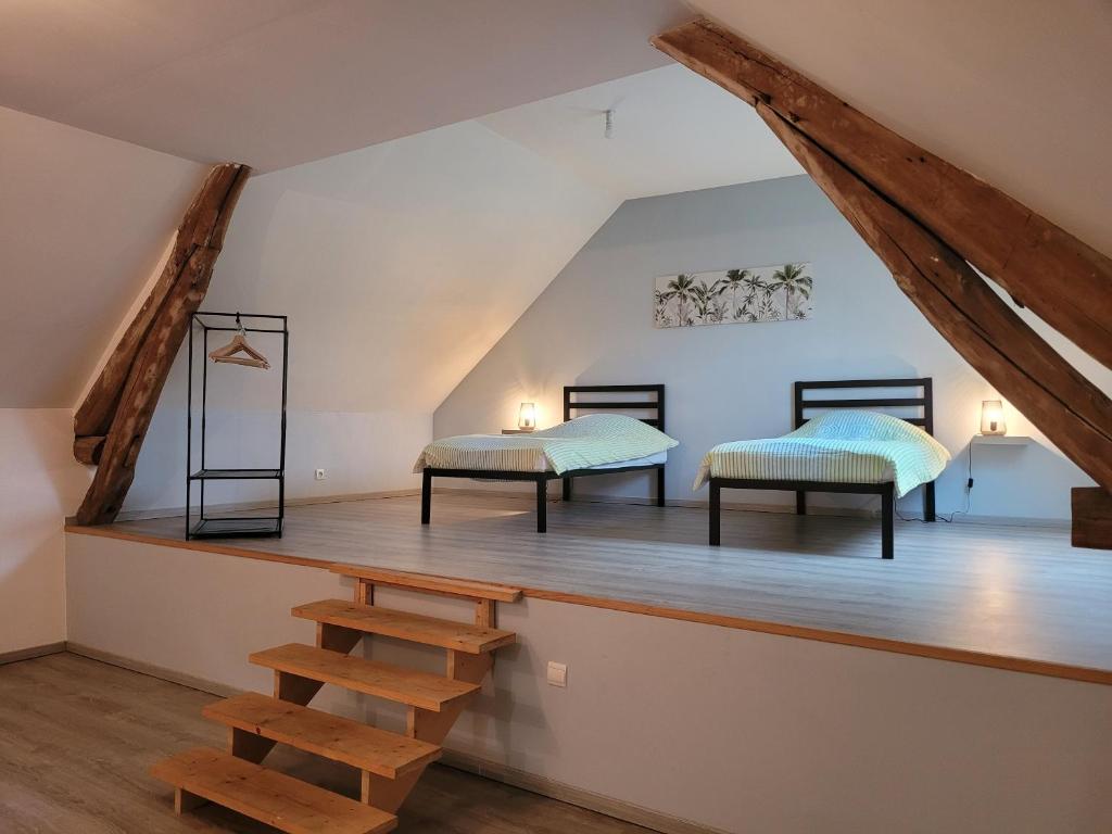 Habitación con 2 camas y suelo de madera. en Un nid pour la nuit, en Bransles