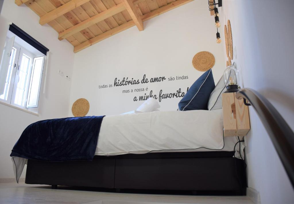 a bedroom with a bed with a sign on the wall at Casinha da Esquina in Amieira
