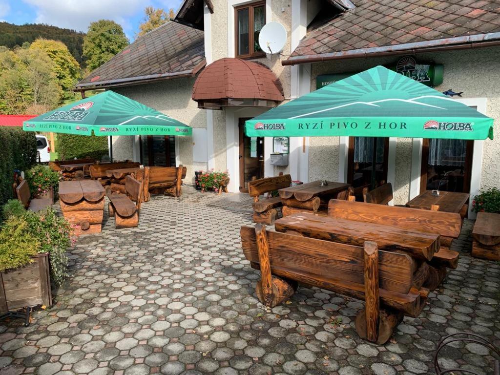 a patio with benches and umbrellas in front of a building at Hospůdka U rybníčku in Karlovice