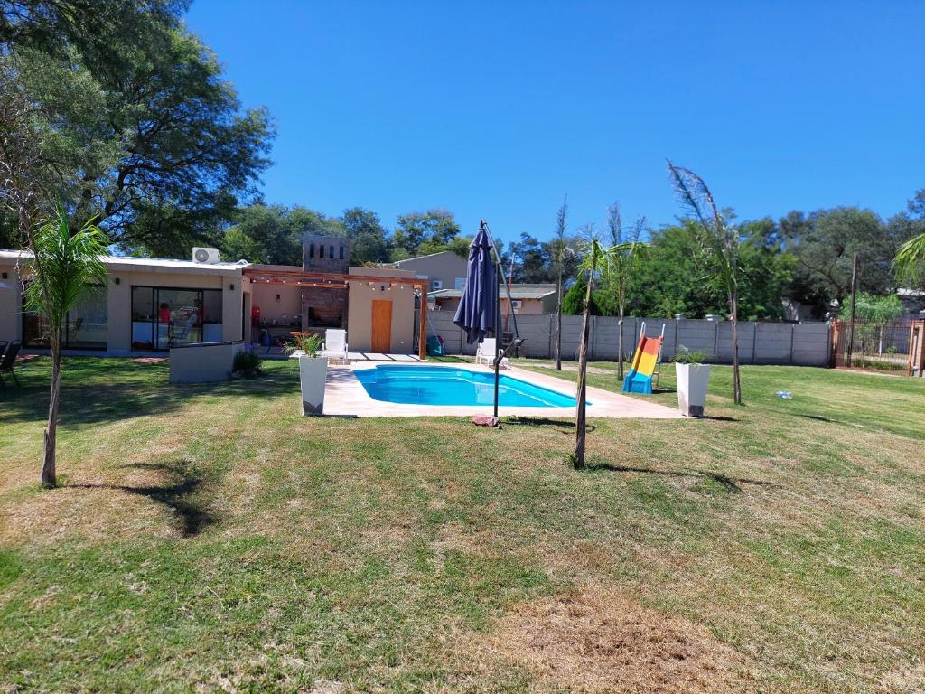 un patio trasero con piscina y sombrilla en Finca La Candelaria en Santiago del Estero