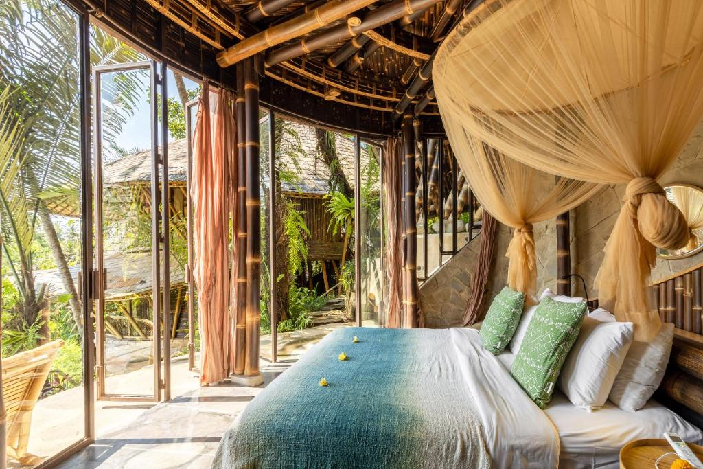 ein Schlafzimmer mit einem Bett in einem Zimmer mit Fenstern in der Unterkunft Eclipse House 4bds Eco Bamboo House Pool RiverView in Bringkit