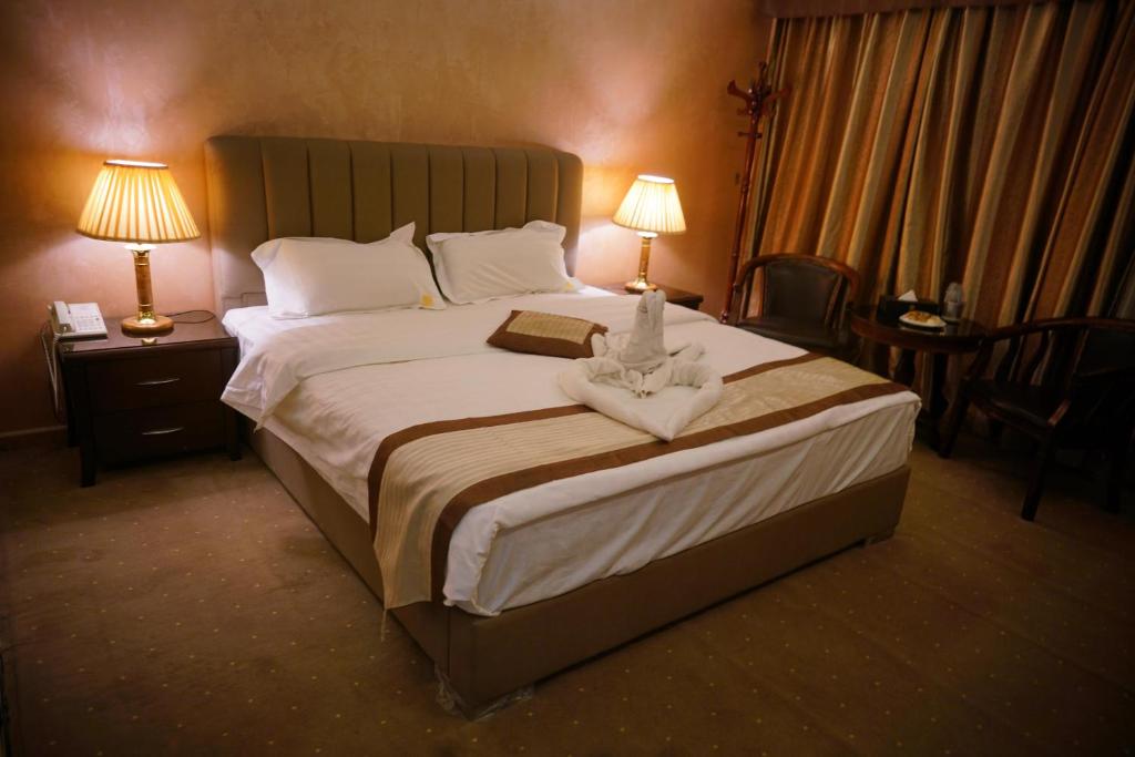 1 cama grande en una habitación de hotel con 2 lámparas en 7 Wonders Hotel en Wadi Musa