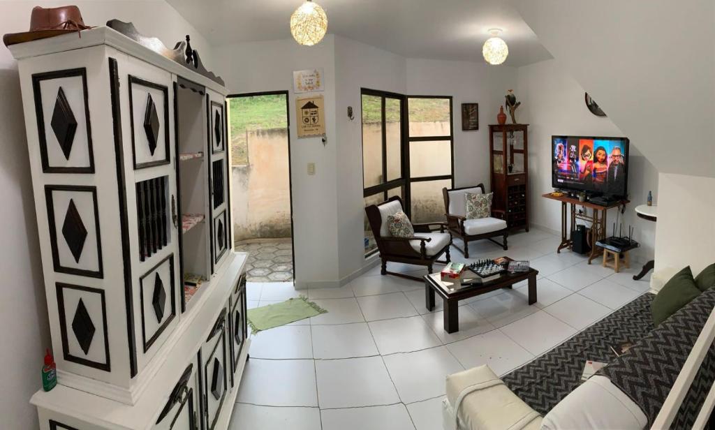 ein Wohnzimmer mit einem Sofa und einem TV in der Unterkunft Duplex com 02 Suítes e Ar-Condicionados in Bananeiras