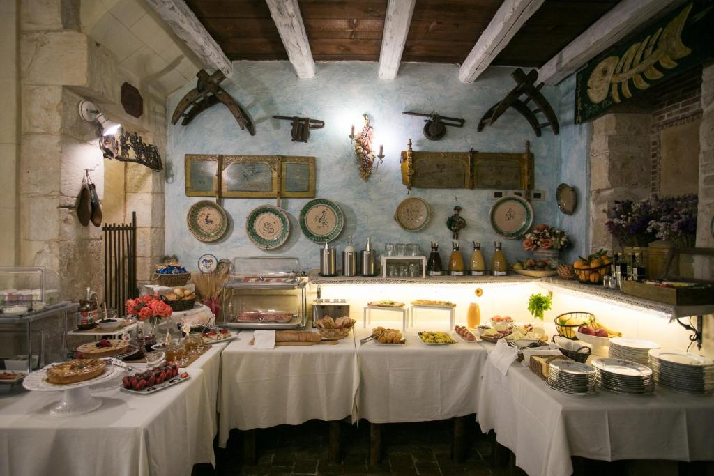 stół z białymi tkaninami stołowymi i jedzeniem w obiekcie Hotel Henry's House w Syrakuzach