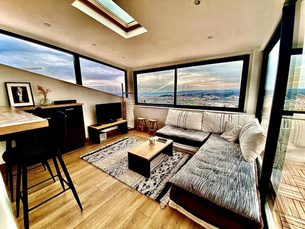 ein Wohnzimmer mit einem Sofa und großen Fenstern in der Unterkunft Appartement d’exception vue panoramique in Nizza