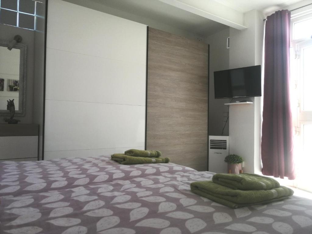 ein Schlafzimmer mit einem Bett mit grünen Kissen darauf in der Unterkunft Studio apartment with private terrace, Jacuzzi & views in Mosta