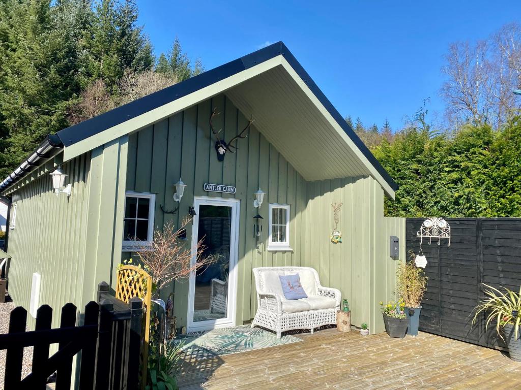a green shed with a chair on a patio at Antler Cabin At Woodlea Spean Bridge in Spean Bridge