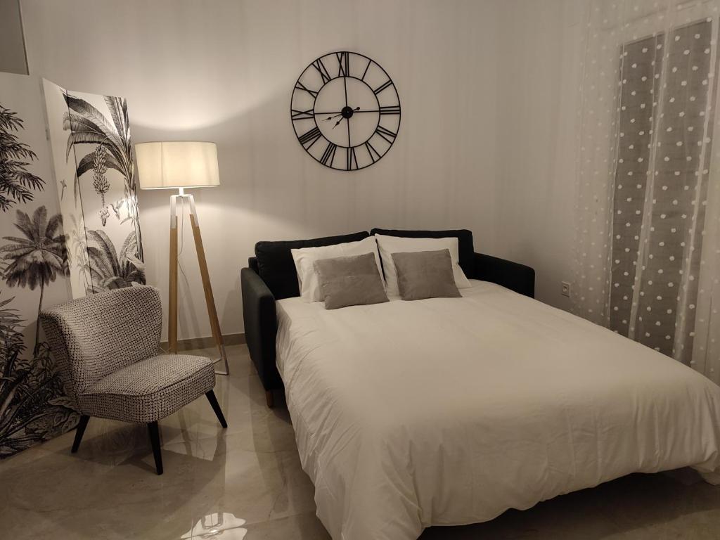 1 dormitorio con 1 cama y reloj en la pared en APARTAMENTO ROMAR CHIC, en Albolote