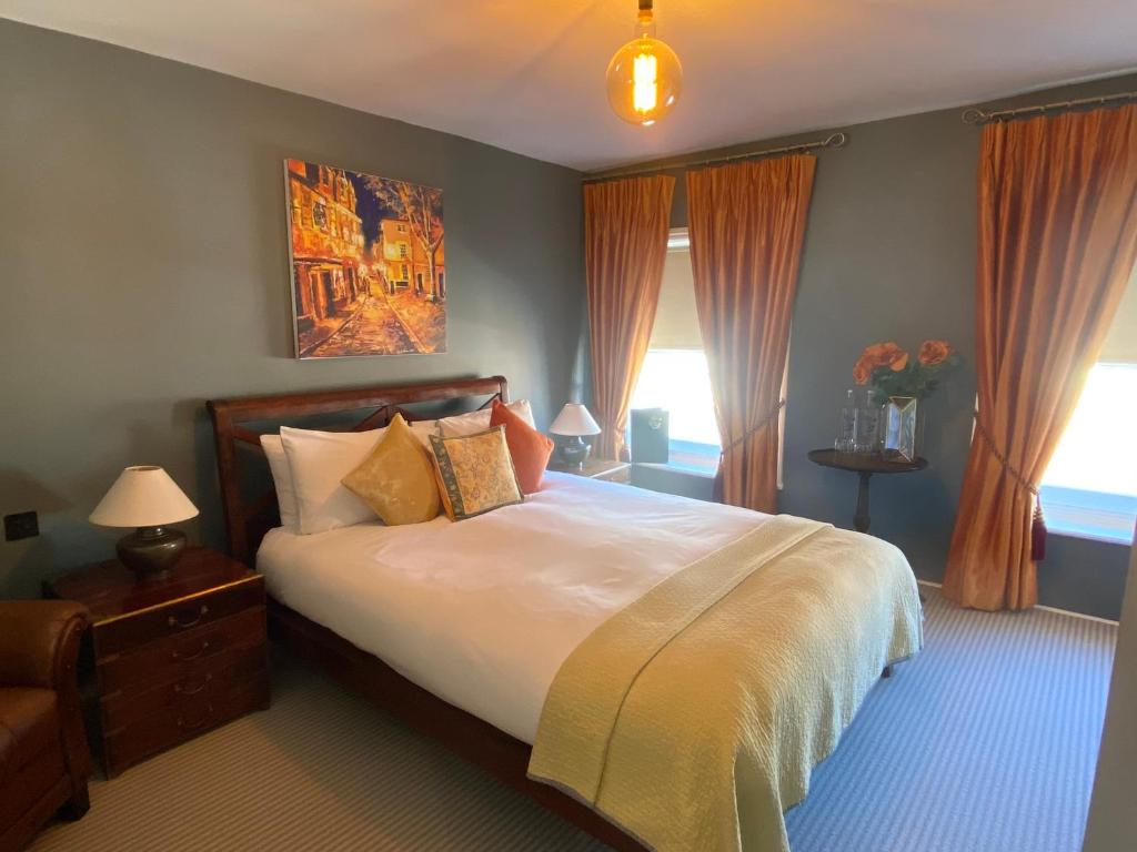 a bedroom with a large white bed with orange curtains at 38 St Giles in Norwich