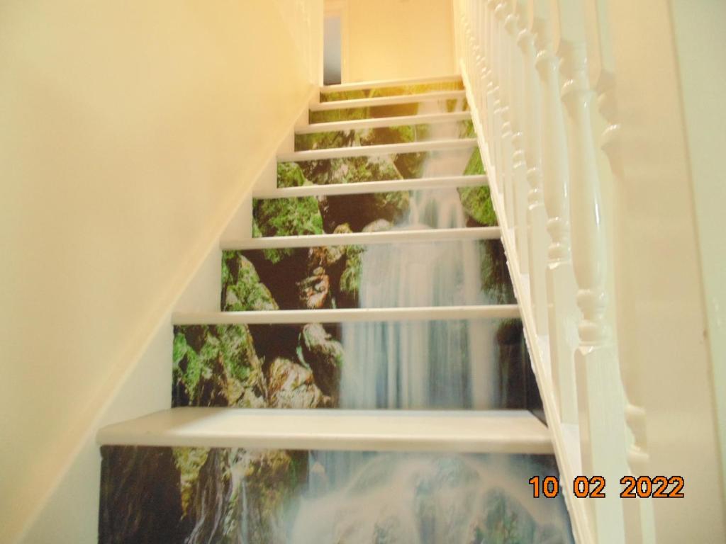 a spiral staircase with a waterfall under the stairs at Two beautiful double bedroom Tulip apartment in Dagenham