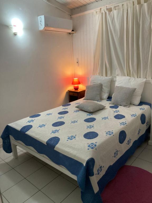 a bedroom with a bed with a blue and white comforter at Maison Jean in Le Gosier