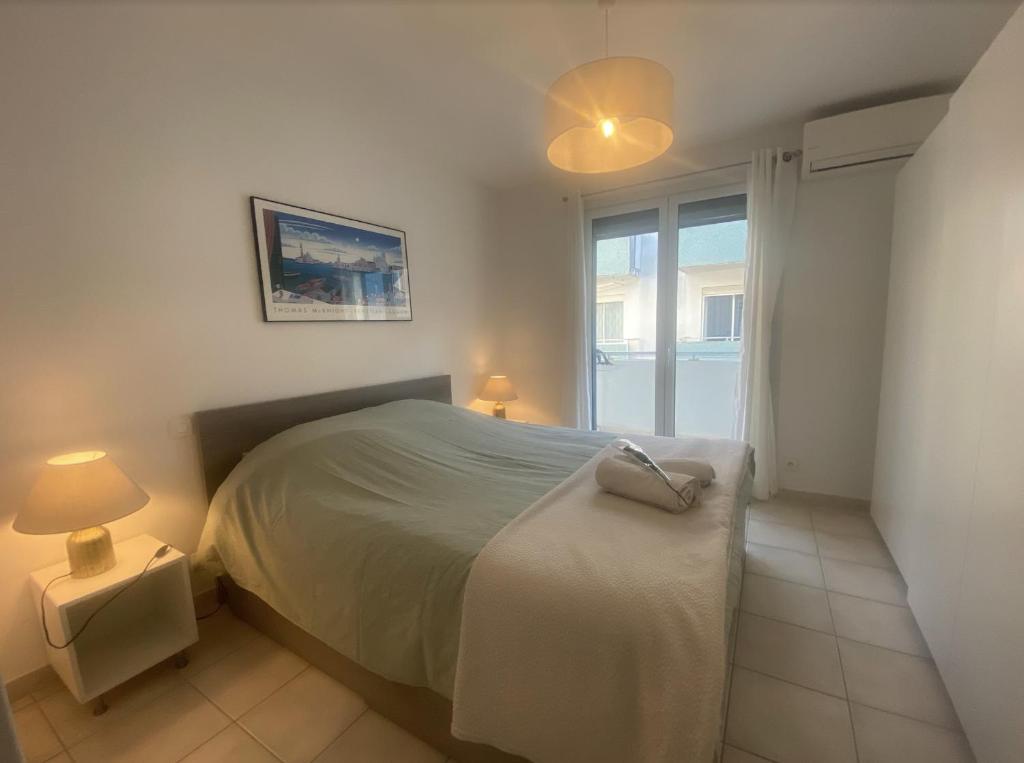 Un dormitorio con una cama grande y una ventana en L'Imperial, en Le Grau-du-Roi