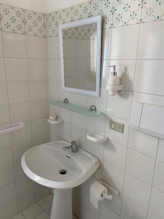 biała łazienka z umywalką i lustrem w obiekcie House sole - Unique Panorama w mieście Lipari