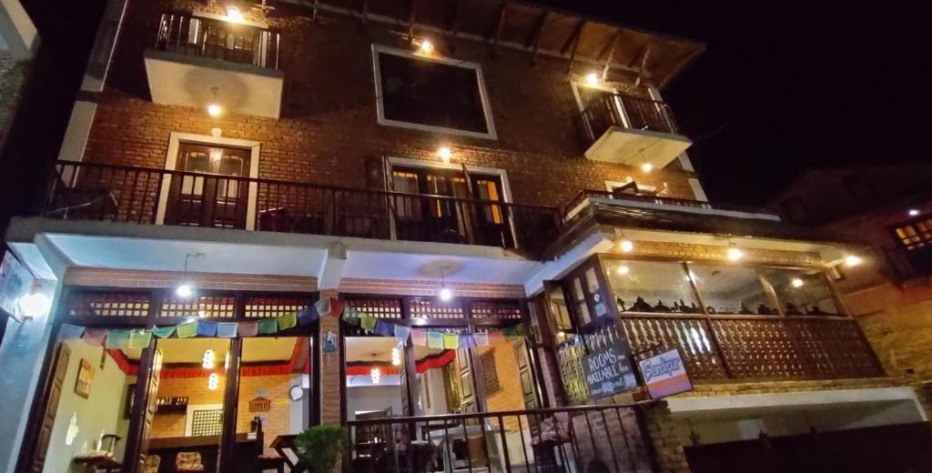een bakstenen gebouw met een balkon in de nacht bij Bandipur Kaushi Inn in Bandipur