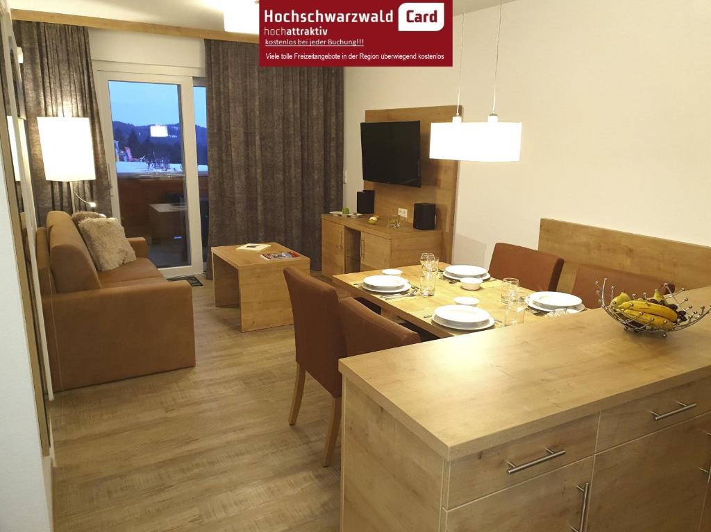 a kitchen and living room with a table and chairs at Enjoy Ferienwohnung Feldberg Grafenmatt in Feldberg