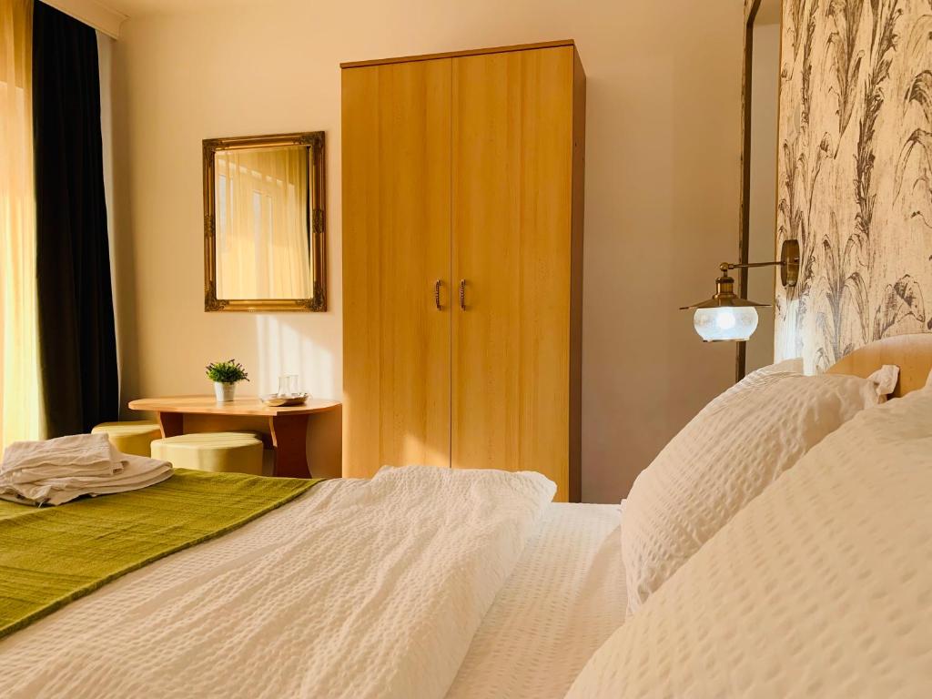 - une chambre avec un lit blanc et une armoire en bois dans l'établissement Casa Neamtu, à Băile Herculane