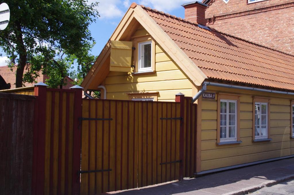 a small yellow house with a wooden fence at Kauba Apartment in Viljandi