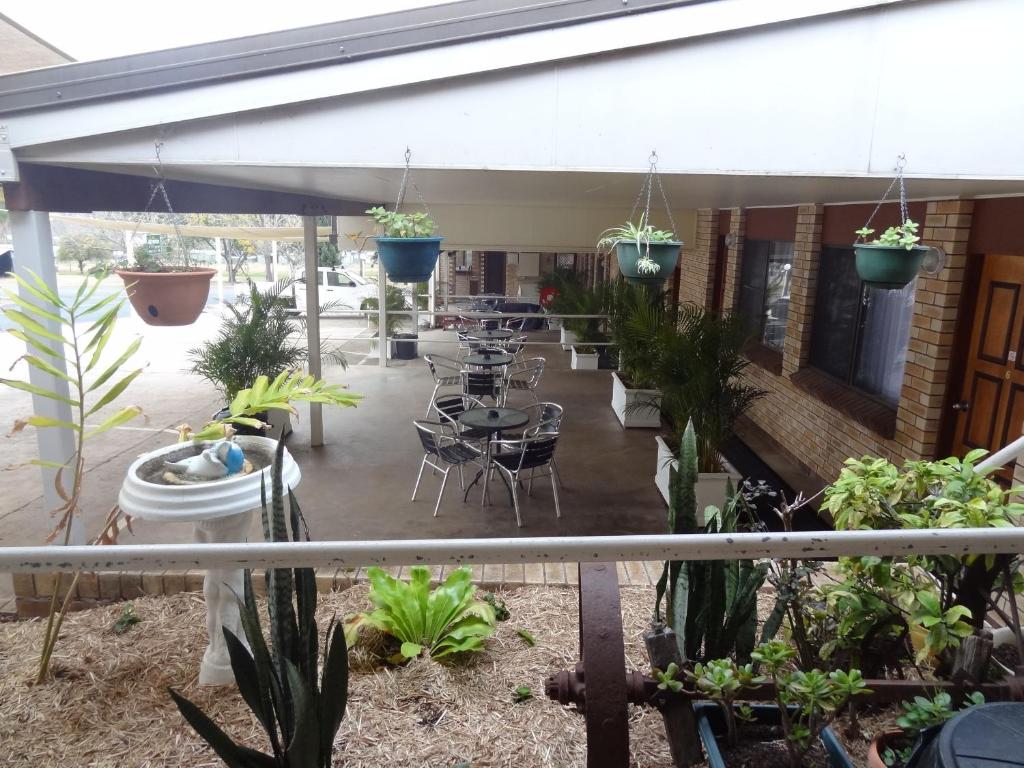 a patio with tables and chairs and potted plants at Goomeri Motel in Goomeri