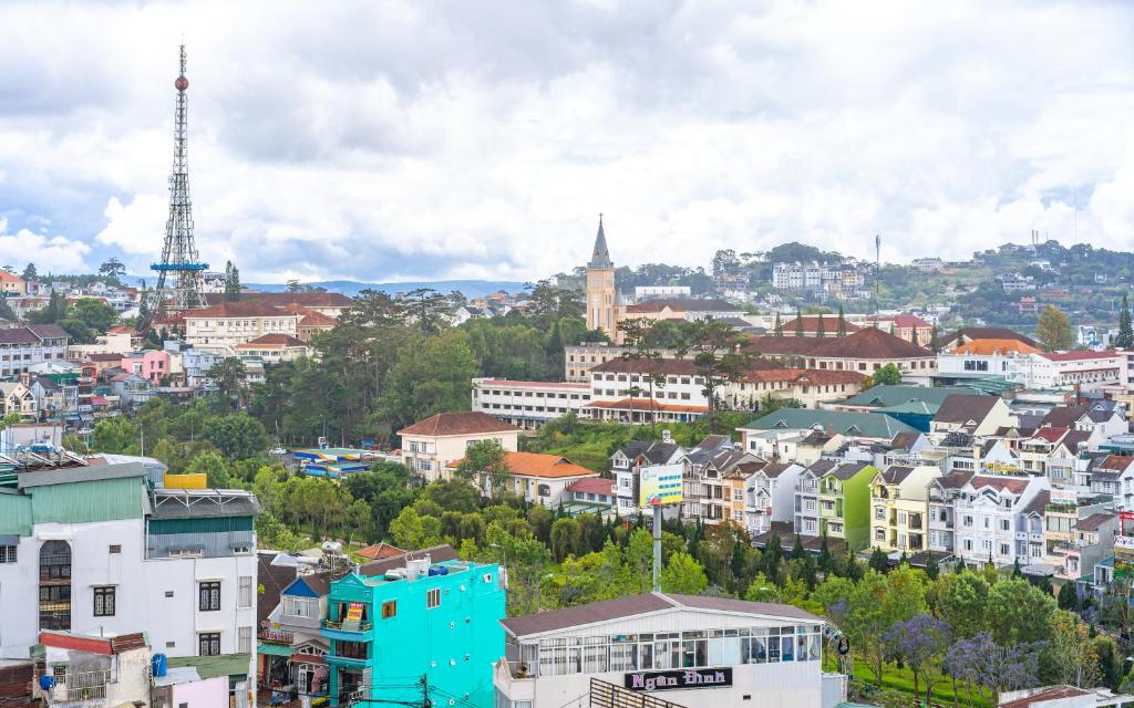 Blick auf eine Stadt mit einem Turm im Hintergrund in der Unterkunft Miền Nhiệt Đới 2 Hotel in Da Lat