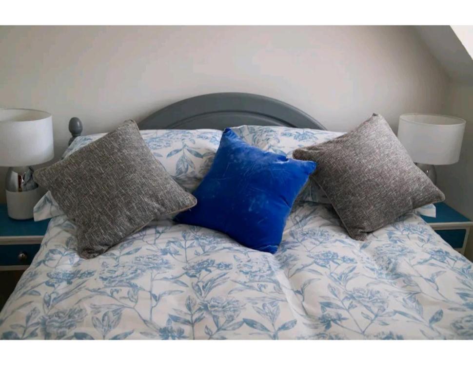 a bed with three pillows on it with two lamps at Pebble Cottage, Cromer in Cromer