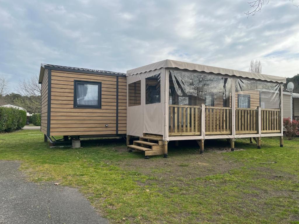 eine Holzhütte mit einer Veranda und einem Zelt in der Unterkunft Bayaïna in Gastes