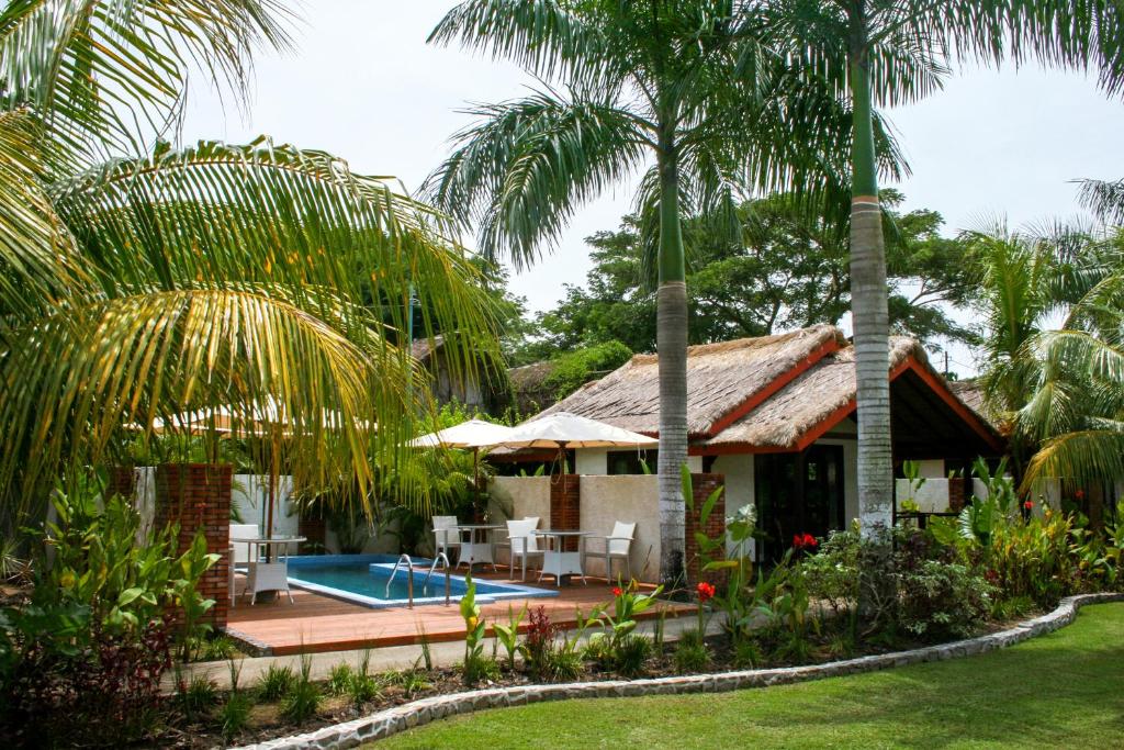 a house with a swimming pool and palm trees at Burudika Bungalows in Selong Belanak