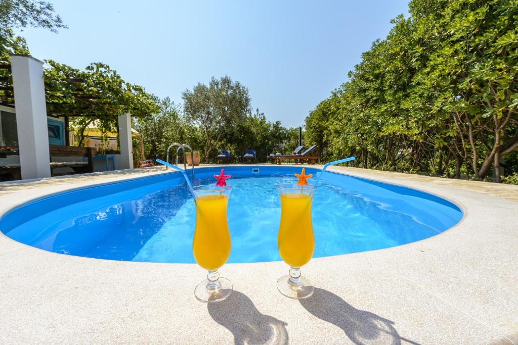 - deux verres de jus d'orange assis à côté de la piscine dans l'établissement Villa Piano, à Mlini