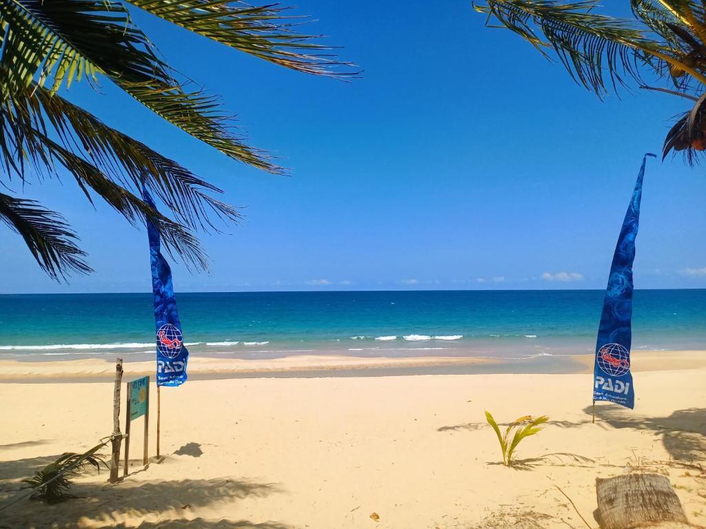 una playa con palmeras y banderas azules. en Juara Cottage, en Tioman Island