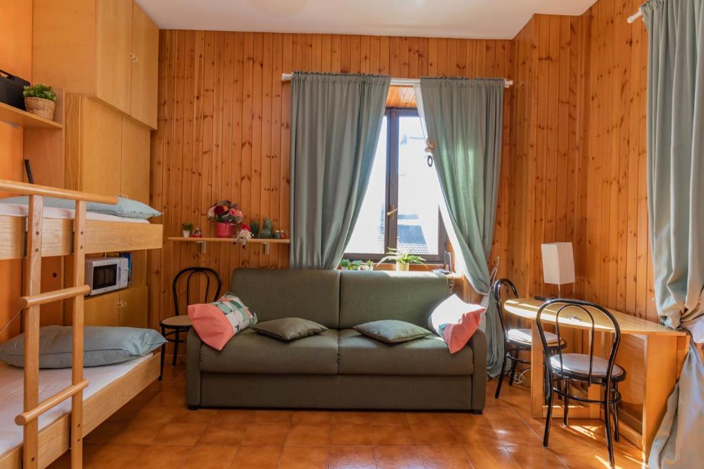 a bedroom with a couch and a bunk bed at Comfort studio centro Aprica vicino piste da sci in Aprica